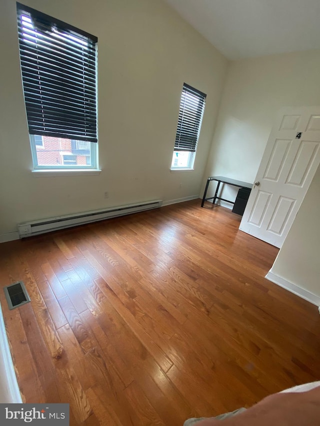 unfurnished living room featuring wood-type flooring and baseboard heating