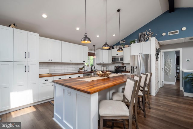 kitchen featuring white cabinets, decorative light fixtures, butcher block counters, and appliances with stainless steel finishes