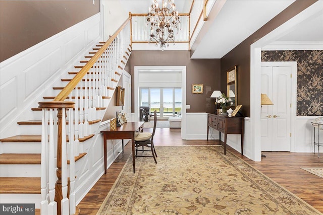 foyer entrance featuring a notable chandelier, hardwood / wood-style flooring, and crown molding