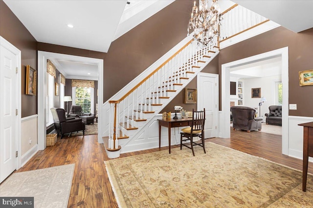 entryway featuring a notable chandelier, hardwood / wood-style floors, a high ceiling, and ornamental molding