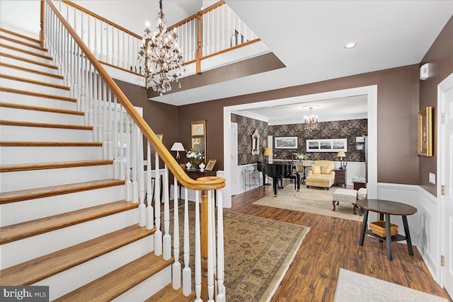 stairs featuring a chandelier, ornamental molding, and dark hardwood / wood-style flooring