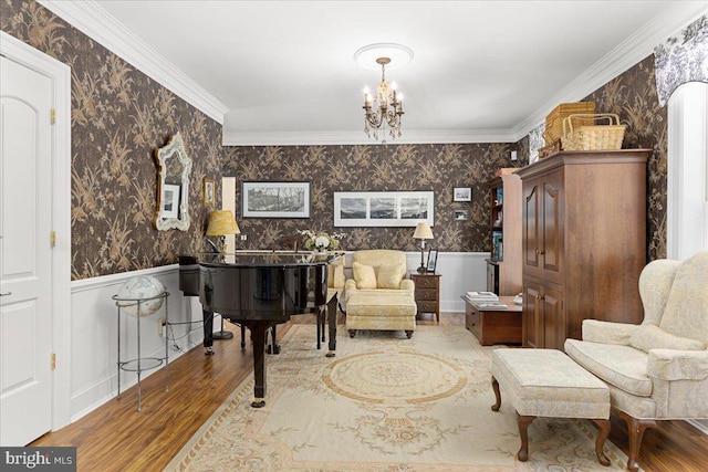 sitting room featuring crown molding, wood-type flooring, and an inviting chandelier