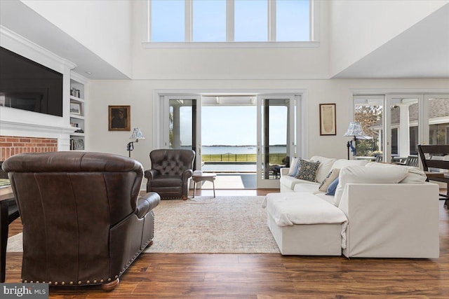 living room with a high ceiling, built in features, and dark hardwood / wood-style flooring