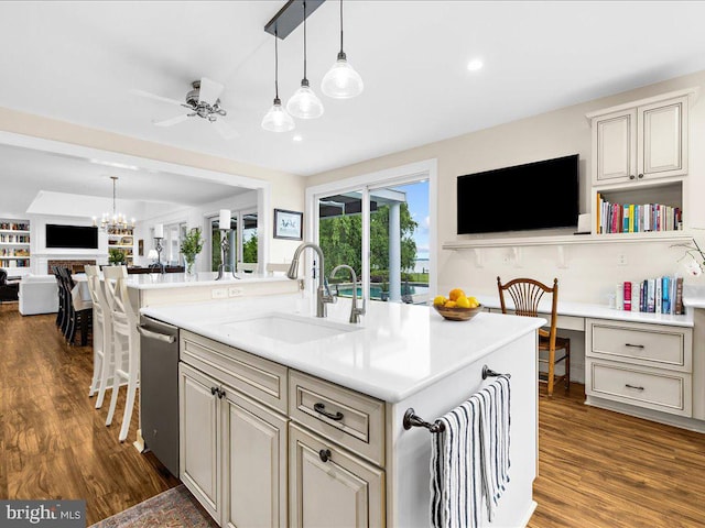 kitchen with hanging light fixtures, a center island with sink, dark hardwood / wood-style flooring, sink, and dishwasher