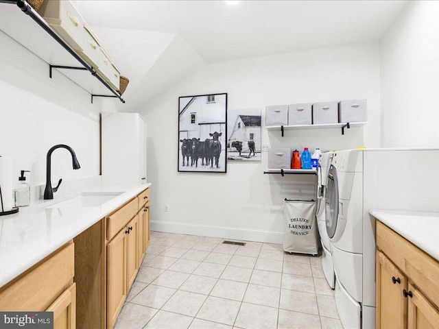 clothes washing area featuring sink, washer and clothes dryer, cabinets, and light tile floors