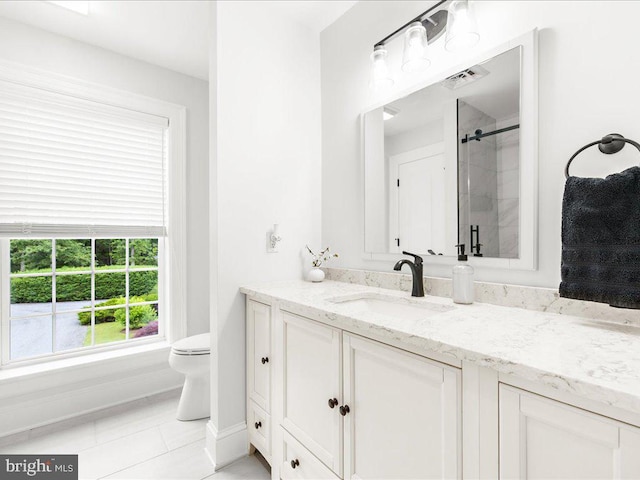 bathroom with tile flooring, vanity with extensive cabinet space, and toilet