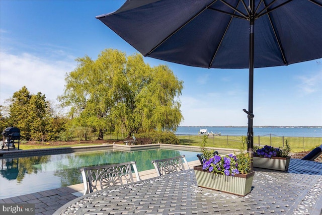 view of pool with a water view and a patio