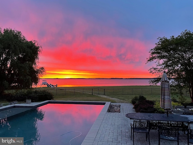 pool at dusk featuring a yard and a patio area