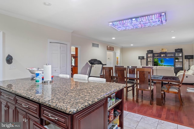 kitchen with dark stone countertops, ornamental molding, light tile floors, and a kitchen island