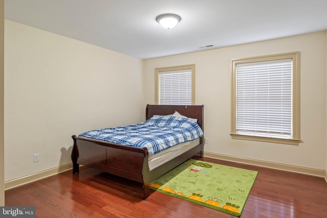 bedroom featuring multiple windows and dark hardwood / wood-style flooring