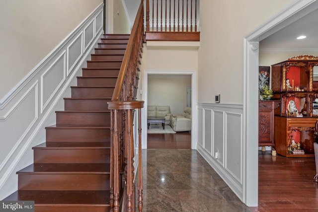 stairway with crown molding and dark tile floors