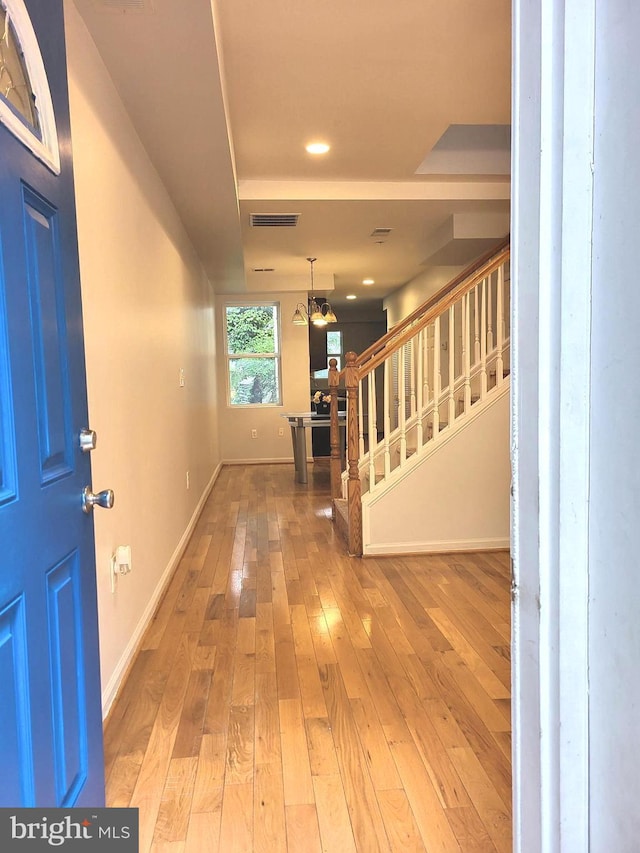 entryway with wood-type flooring and a notable chandelier