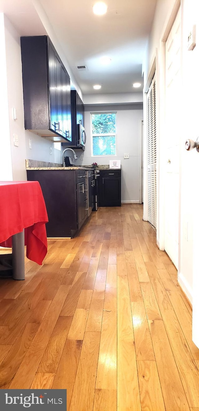 kitchen with light stone countertops, sink, and light wood-type flooring