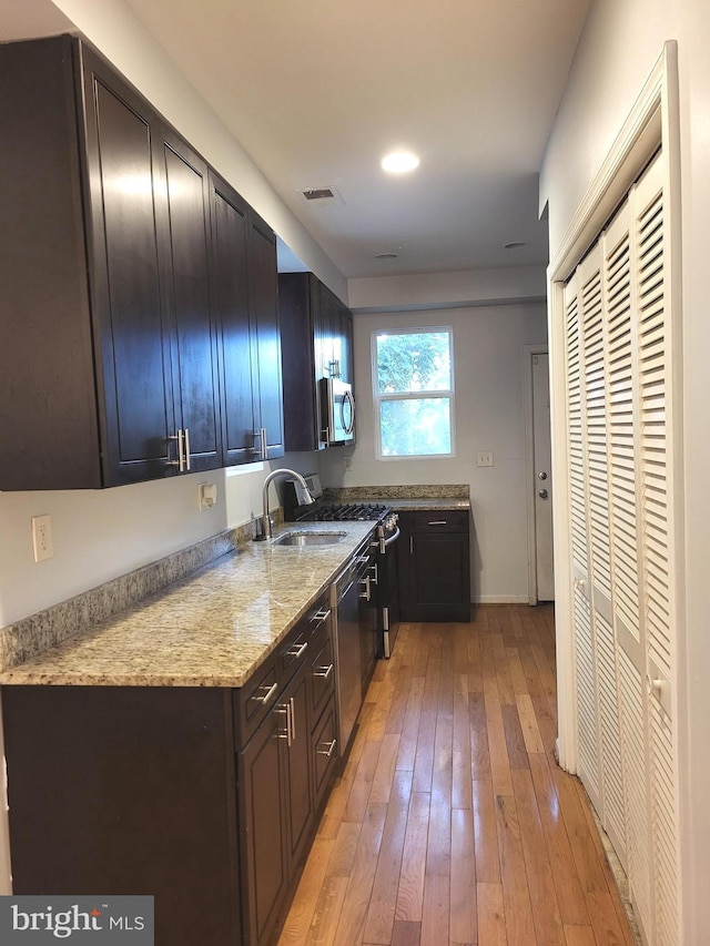 kitchen featuring light stone counters, sink, light hardwood / wood-style flooring, and stainless steel appliances