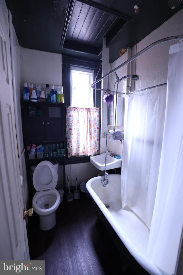 bathroom with hardwood / wood-style flooring, toilet, and a bathtub