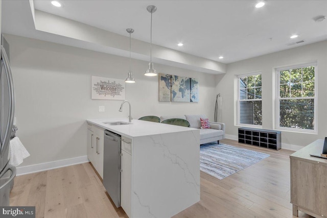 kitchen with kitchen peninsula, light stone counters, stainless steel dishwasher, light hardwood / wood-style floors, and sink