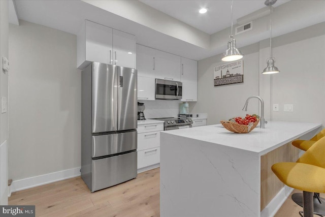 kitchen featuring kitchen peninsula, light hardwood / wood-style floors, white cabinetry, and stainless steel appliances