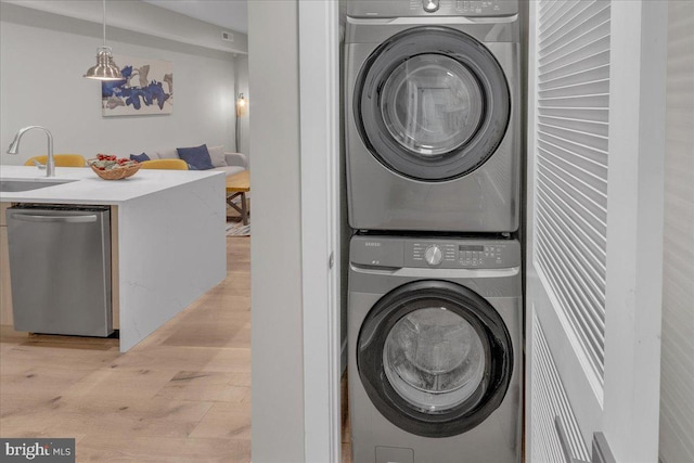 laundry area with light hardwood / wood-style floors, sink, and stacked washer / dryer