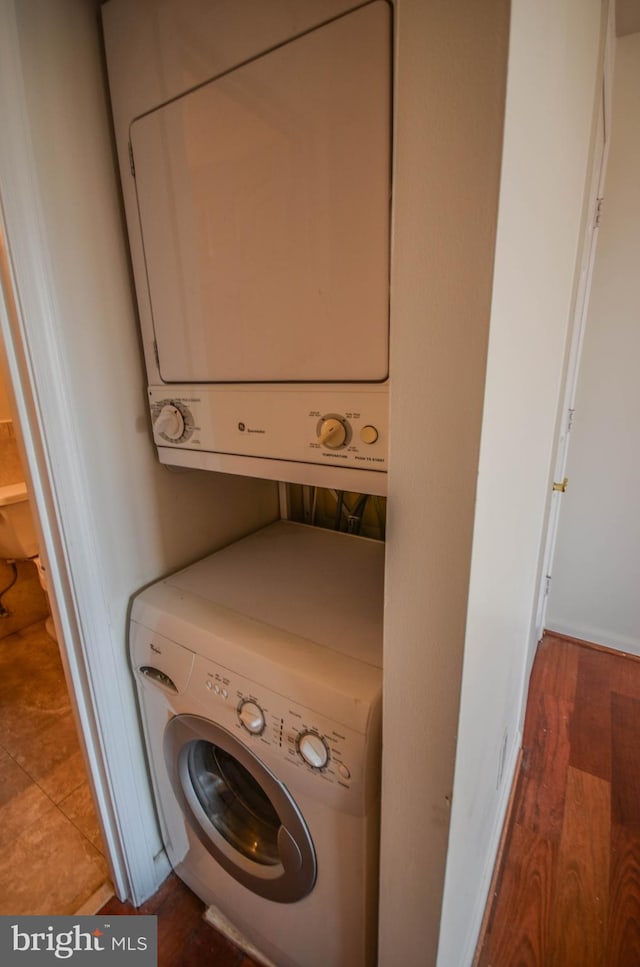 laundry room with stacked washing maching and dryer and tile floors