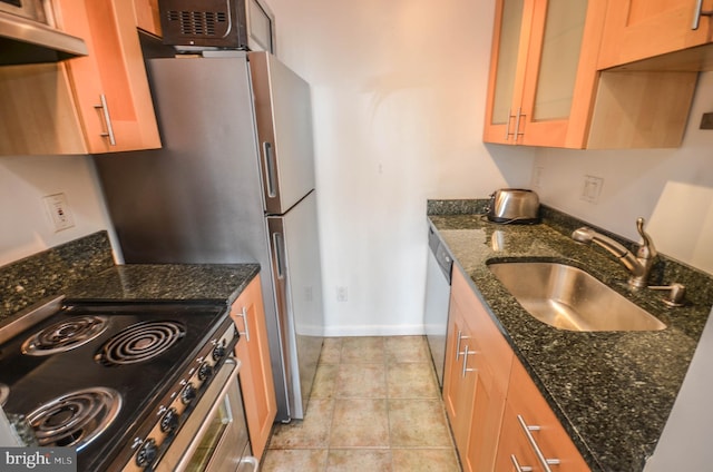 kitchen with dark stone countertops, sink, stove, and light tile floors