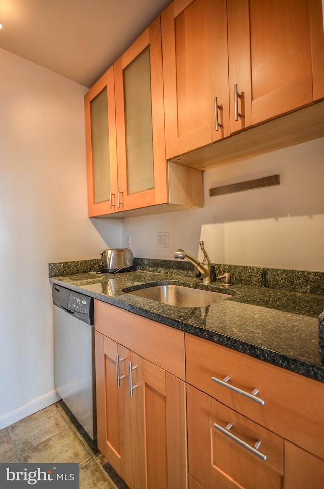 kitchen with sink, dishwasher, light tile flooring, and dark stone countertops