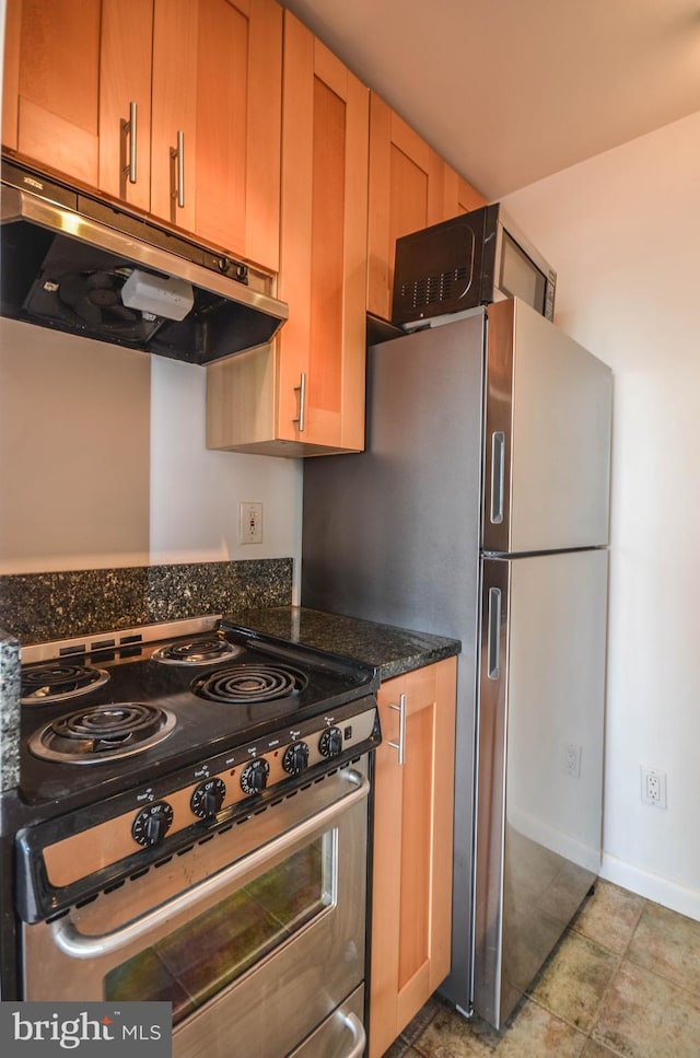 kitchen with range, light tile flooring, stainless steel refrigerator, and dark stone countertops