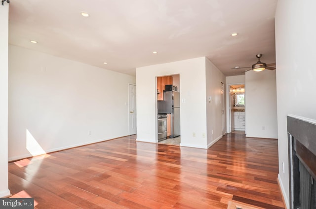 unfurnished living room featuring ceiling fan and hardwood / wood-style floors