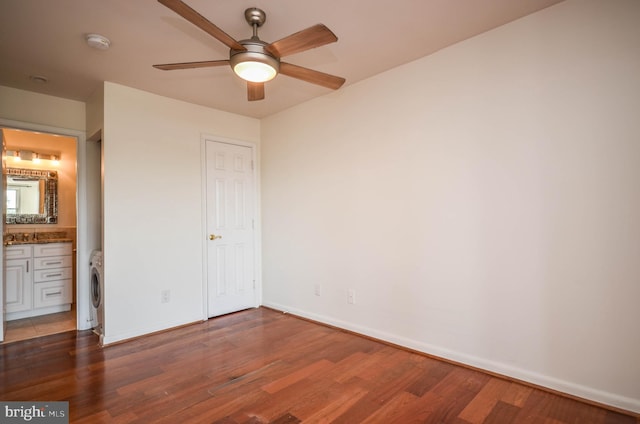 unfurnished bedroom featuring ceiling fan, ensuite bathroom, washer / clothes dryer, and dark wood-type flooring