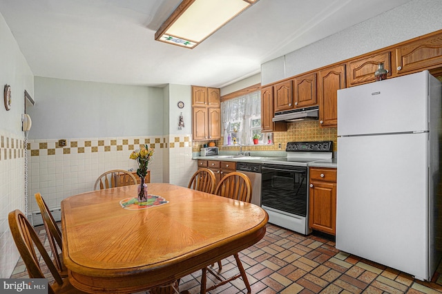 kitchen with white appliances, tile walls, and sink