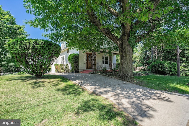 view of property hidden behind natural elements featuring a front lawn and a porch