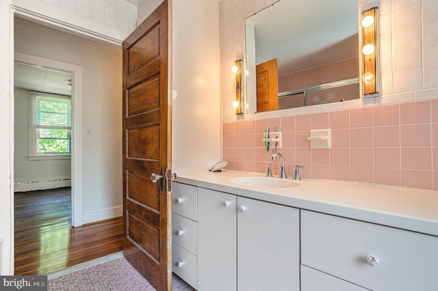 bathroom with hardwood / wood-style floors, vanity, backsplash, walk in shower, and a baseboard radiator