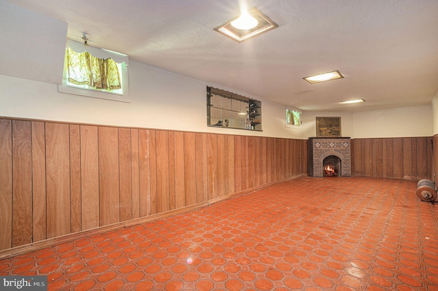 basement with a fireplace, a textured ceiling, and wood walls