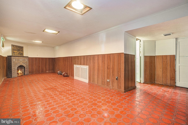 basement with a fireplace, ornamental molding, a textured ceiling, and wooden walls