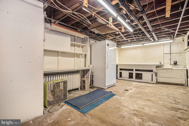 basement with a workshop area and white refrigerator