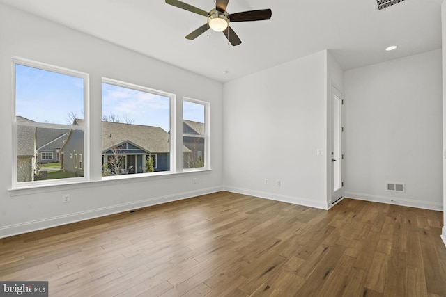 spare room with a healthy amount of sunlight, ceiling fan, and hardwood / wood-style flooring