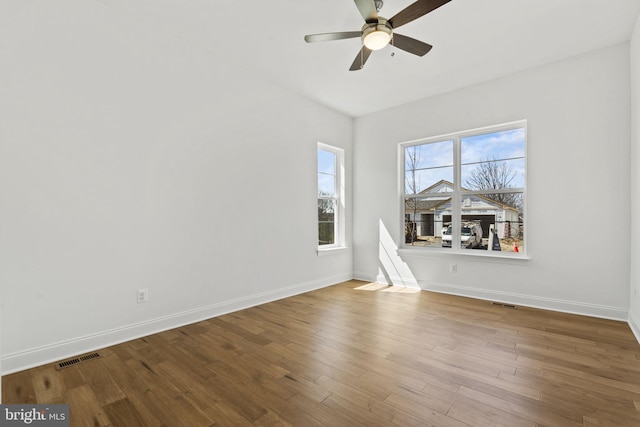 spare room with plenty of natural light, ceiling fan, and hardwood / wood-style floors