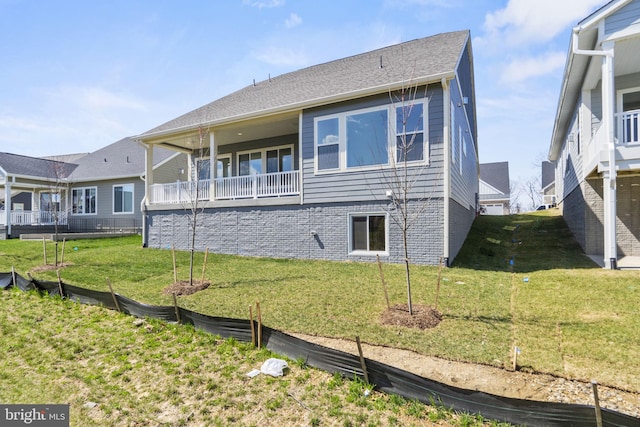 back of property with a yard and a balcony