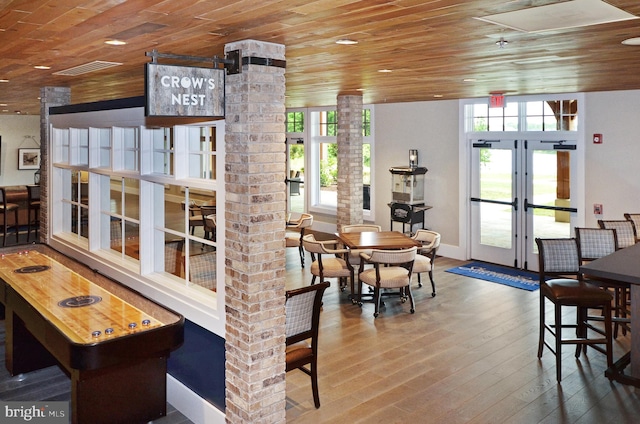 dining area with french doors, brick wall, wooden ceiling, hardwood / wood-style floors, and ornate columns