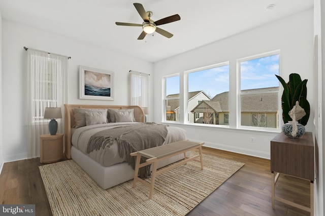 bedroom with dark wood-type flooring, multiple windows, and ceiling fan