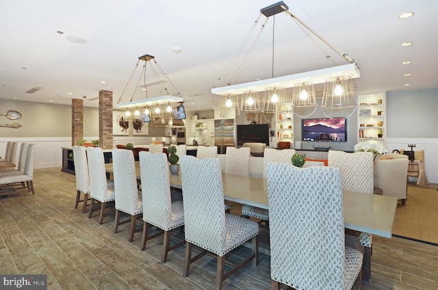 dining space with built in features, hardwood / wood-style floors, and brick wall