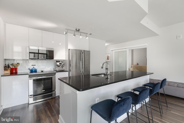 kitchen featuring a center island with sink, sink, decorative backsplash, white cabinetry, and stainless steel appliances