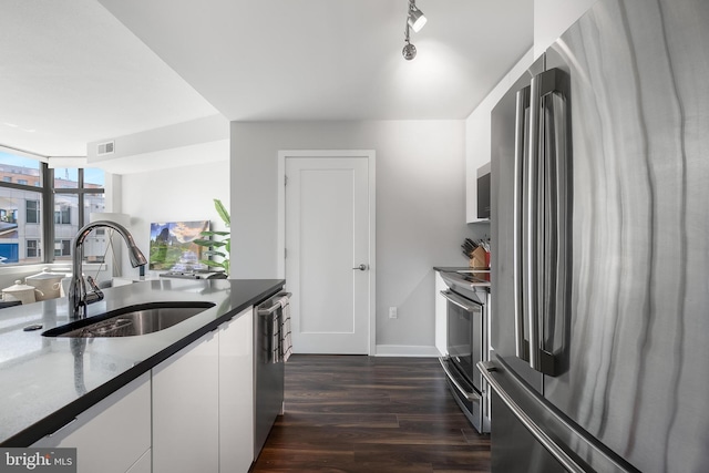 kitchen featuring white cabinetry, sink, a wall of windows, dark hardwood / wood-style flooring, and appliances with stainless steel finishes