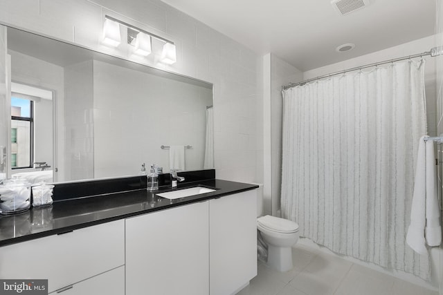 bathroom featuring a shower with shower curtain, vanity, tile walls, tile patterned flooring, and toilet