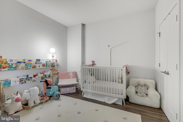 bedroom featuring dark hardwood / wood-style floors and a nursery area