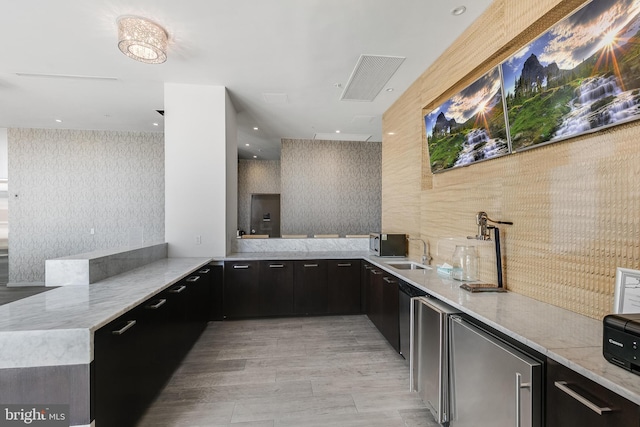 kitchen with kitchen peninsula, light stone counters, and sink