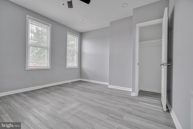 unfurnished bedroom featuring a closet, light hardwood / wood-style floors, and ceiling fan