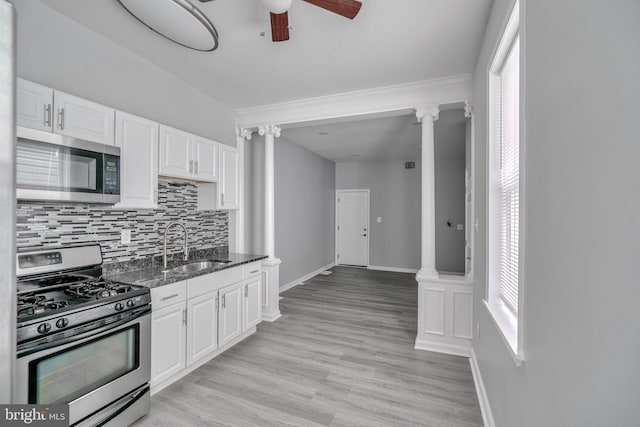 kitchen with white cabinets, appliances with stainless steel finishes, decorative columns, and sink