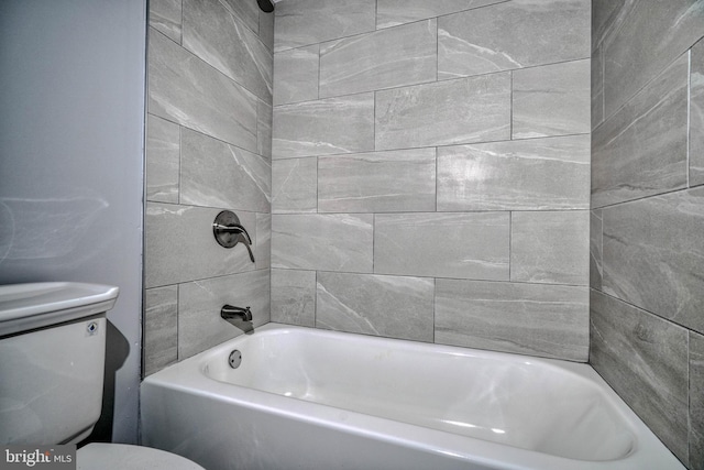 bathroom featuring tiled shower / bath and toilet