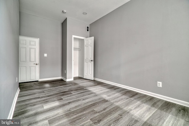 unfurnished bedroom featuring hardwood / wood-style floors and a towering ceiling