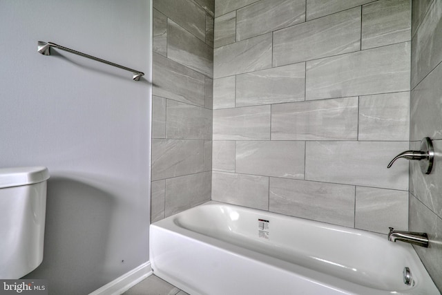 bathroom featuring tiled shower / bath combo and toilet